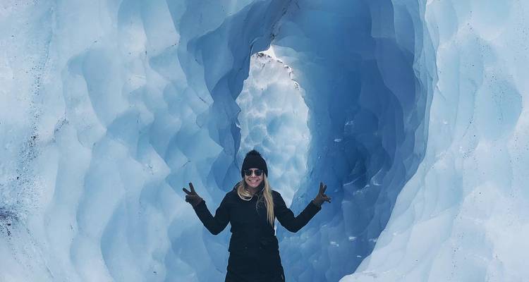 Personne en équipement de plein air posant dans une grotte glacée.