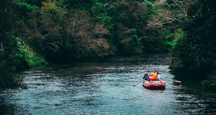 Des gens faisant du rafting entourés de verdure.