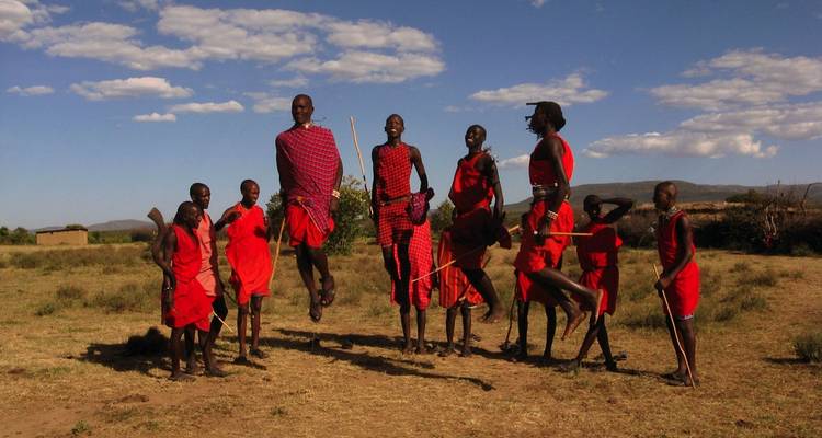 Group of Maasai men in traditional garments jumping in a typical dance.