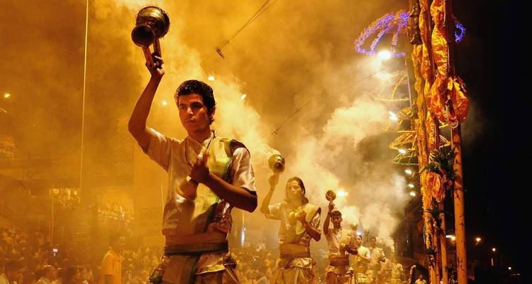 Anhänger führen Aarti durch, während Rauch die Luft erfüllt.