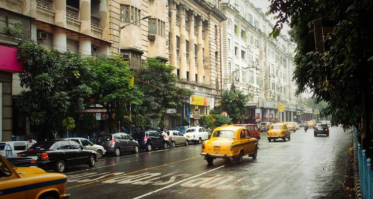 Calle concurrida en Kolkata con icónicos taxis amarillos.