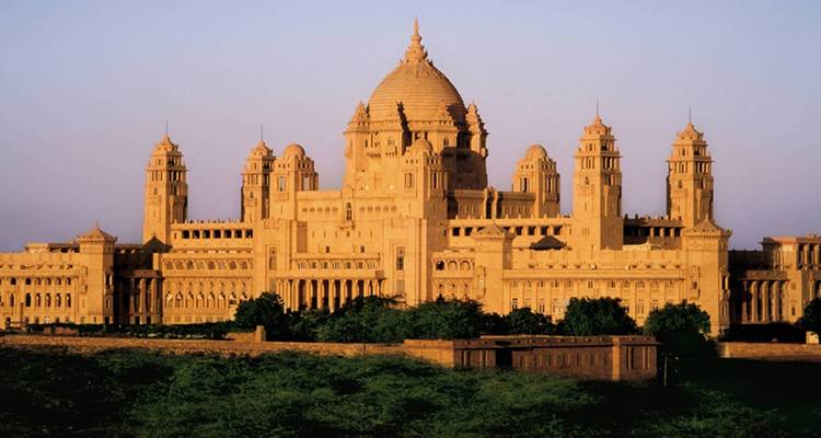Een majestueus paleis met koepels en torens omringd door groen.