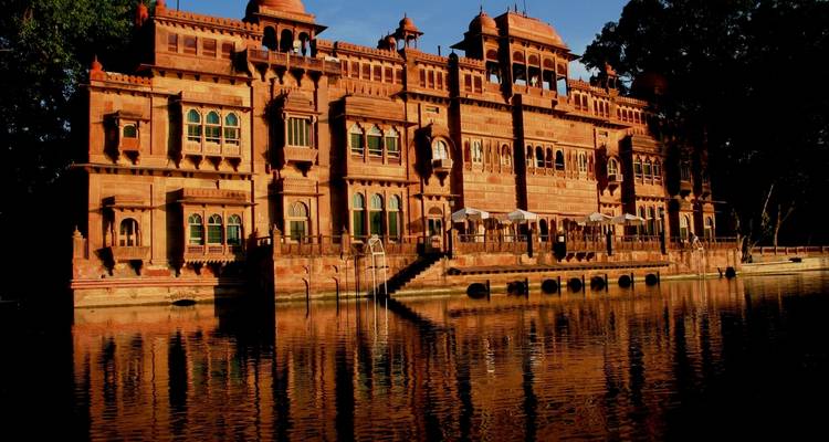 Een groots paleis met sierlijke ramen bij een stilstaand meer dat de structuur weerspiegelt.