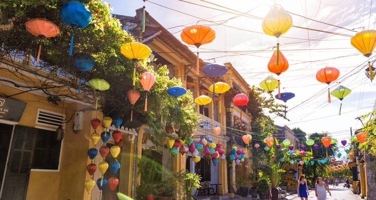 Straatbeeld met kleurrijke lantaarns die boven hangen en mensen die lopen.