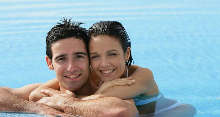 Pareja disfrutando tiempo juntos en una piscina.