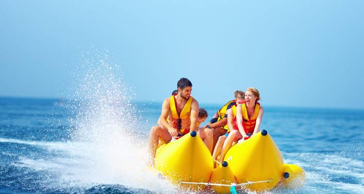 Grupo montando en una banana acuática en el mar.