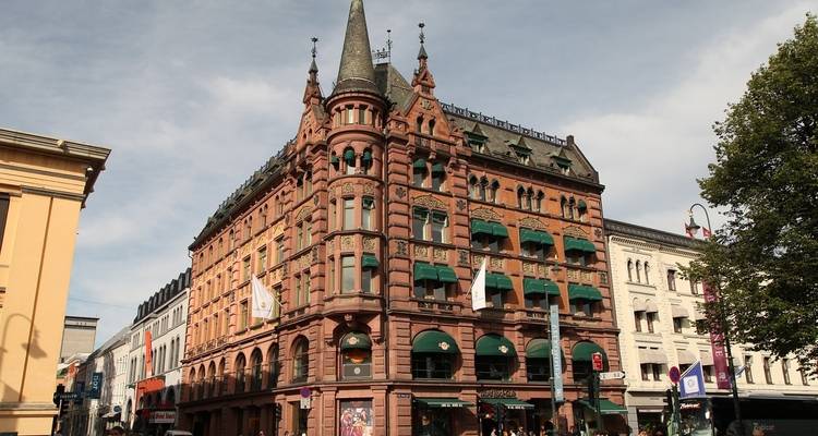 Bâtiment vintage en briques avec une architecture ornementée dans une rue animée.