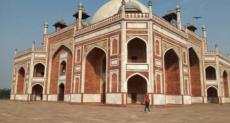 Man walking by a grand, historic structure.