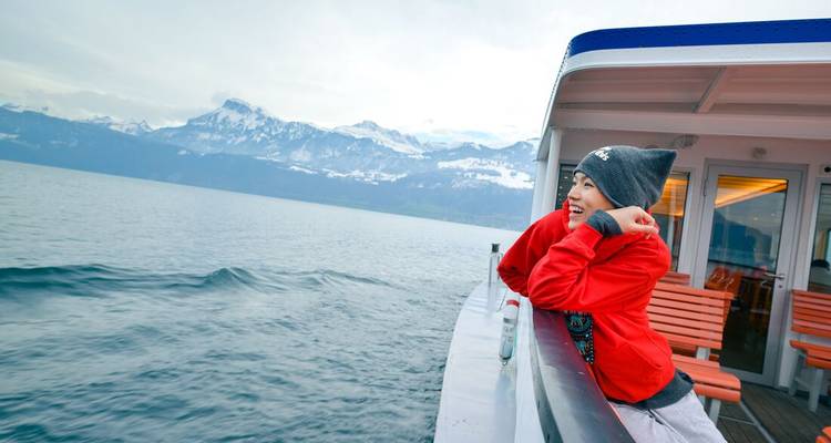 Personne profitant de la vue depuis un bateau avec des montagnes enneigées en arrière-plan.