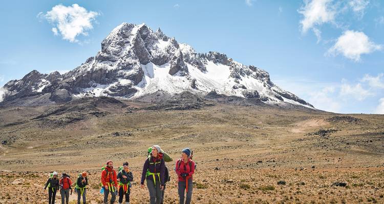 Hikers walking towards a snow-capped mountain in Tanzania
