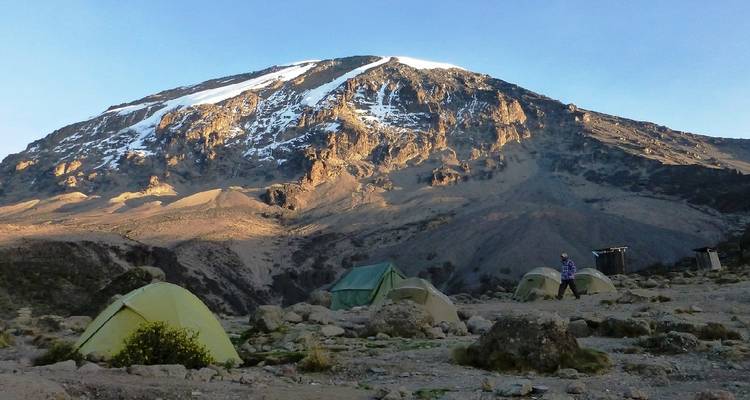 Mountain campsite with tents and Kilimanjaro in background.