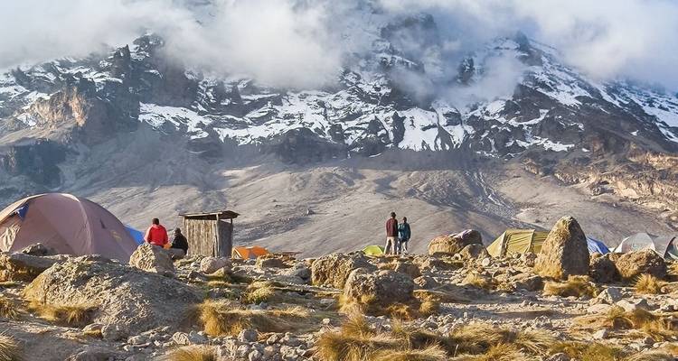 Campers with tents on rocky terrain at Kilimanjaro.