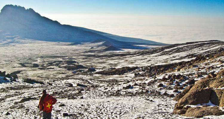 Person, die auf einer schneebedeckten Landschaft mit Bergblick steht.