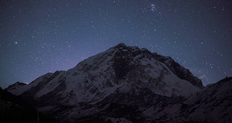 Une montagne enneigée sous un ciel étoilé.