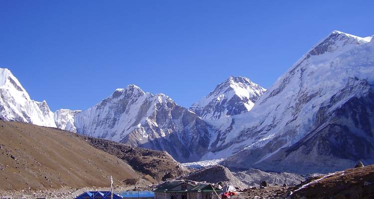 Montagnes enneigées sous un ciel bleu dégagé avec des villages en contrebas.
