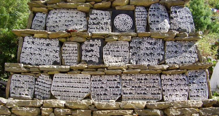 Pierres de prière gravées empilées en mur.