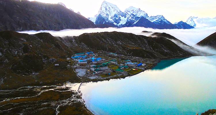 Un village niché parmi des montagnes enneigées et un lac serein.