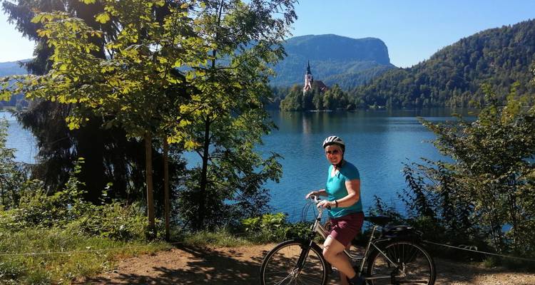 Un ciclista posa junto a las aguas esmeralda del Lago Bled con la iglesia de la isla de fondo