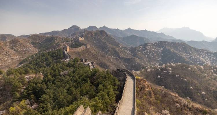 Vista panorámica primaveral de la Gran Muralla serpenteando sobre crestas montañosas florecidas en Jinshanling.