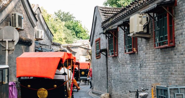 Rickshaws con toldos rojos se alinean en un estrecho callejón hutong de ladrillo gris en Beijing.