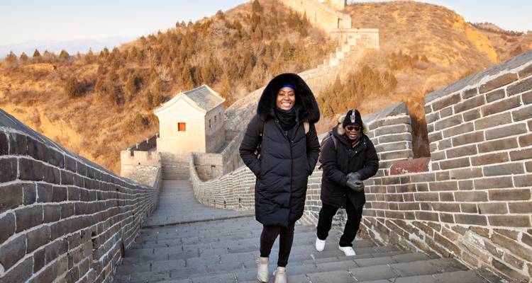 Dos viajeros disfrutando de una sección tranquila de la Gran Muralla en un día fresco.