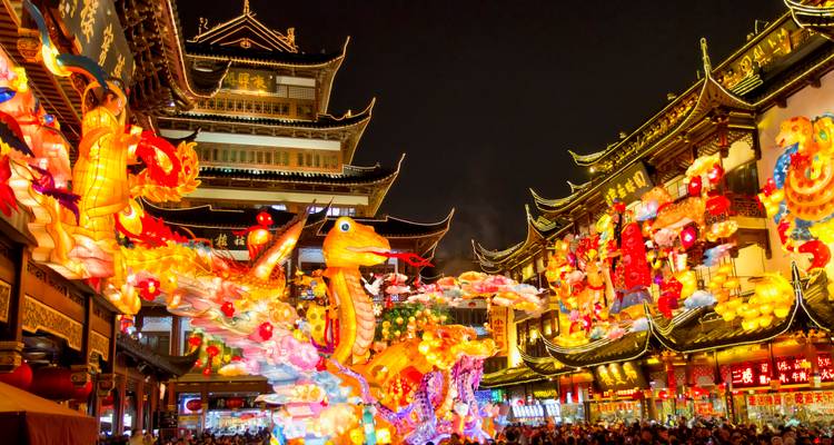 Vibrante escena nocturna de una calle de templo chino iluminada con faroles con una instalación de dragón resplandeciente y multitudes abajo.