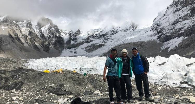 Groupe de personnes debout près d'un glacier avec des sommets enneigés.