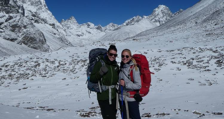 Deux randonneurs dans la neige avec des montagnes en arrière-plan.