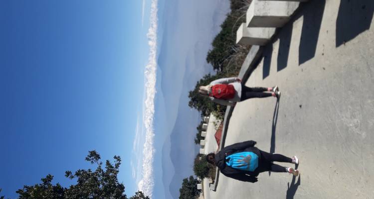 Deux personnes marchant le long d'un sentier de montagne avec des sommets enneigés.