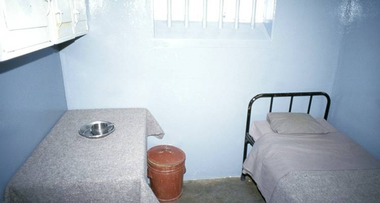 Simple prison cell with a bed and small table.