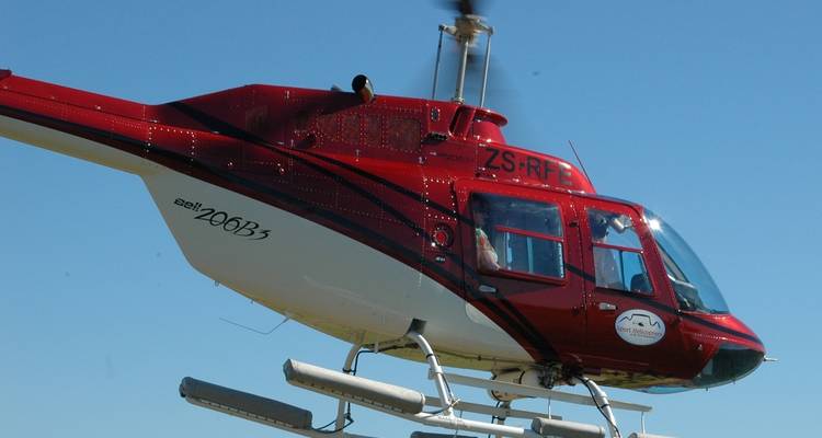 Hélicoptère rouge volant dans un ciel bleu clair.