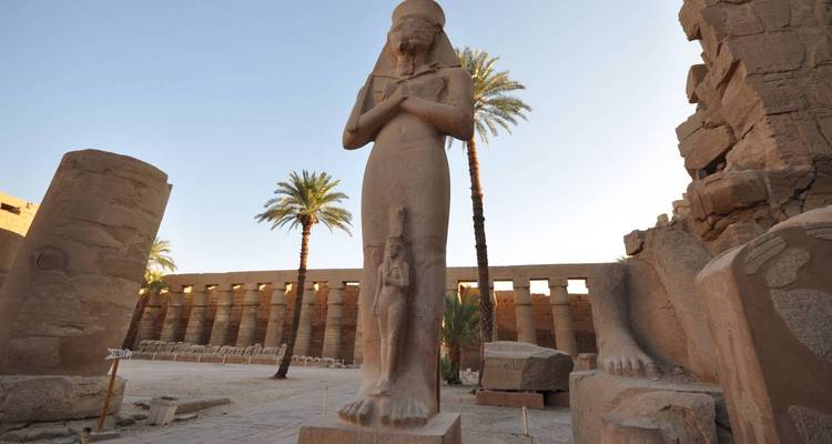 Tall ancient Egyptian statue surrounded by pillars.