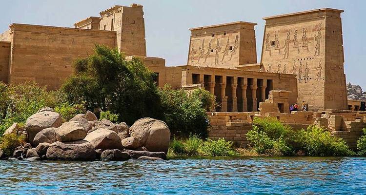 Temple ruins by a river with lush greenery.