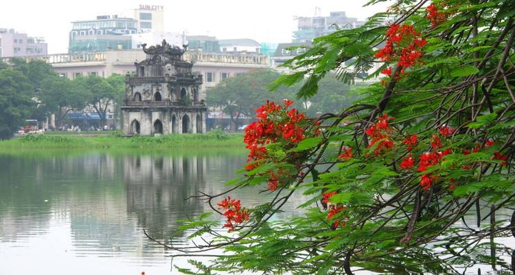 Historic tower on a lake with flowering trees.