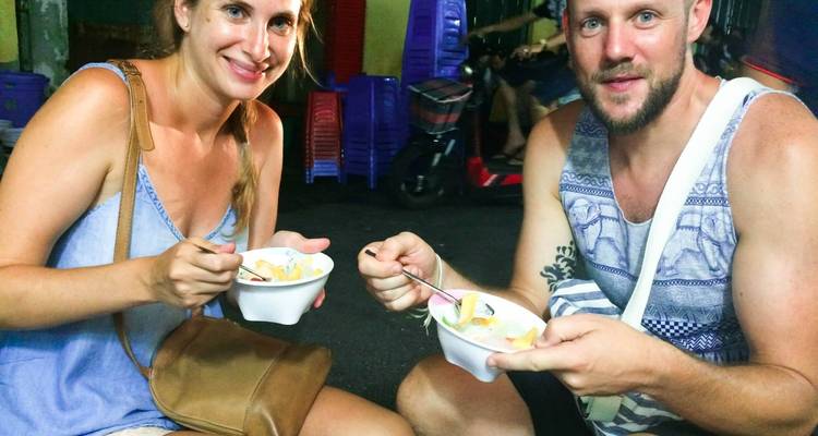 Couple eating dessert on the street at night.