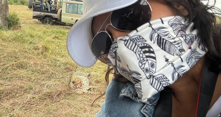 Person wearing mask and sunglasses, with a cheetah in the background.