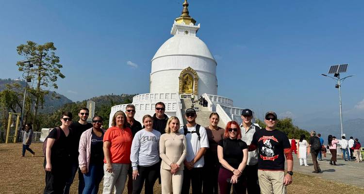 Groupe de touristes posant devant un grand stupa.