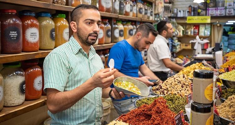 Market stall with vendor offering spice samples.