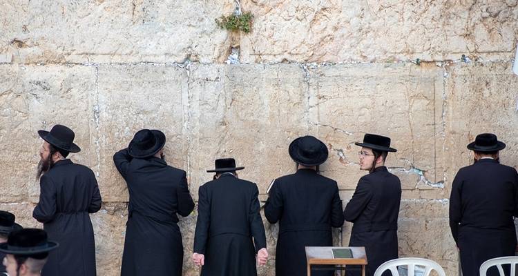 Worshippers at the Western Wall in traditional attire.