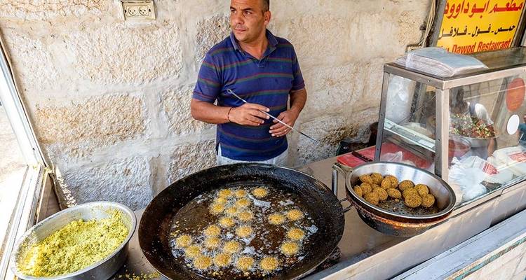 Street vendor frying food at a roadside stall.