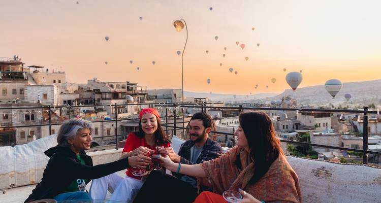 Des gens profitant d'un toit-terrasse avec des montgolfières en arrière-plan