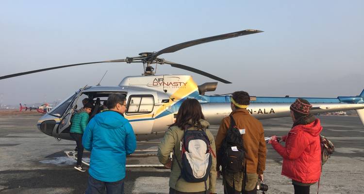 Group of people standing near a helicopter on a helipad.