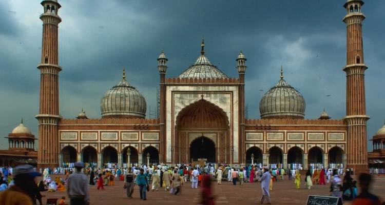 Crowd gathered at Jama Masjid with a dramatic cloudy sky.