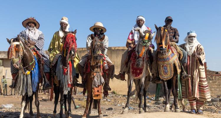 Groupe de personnes en tenue traditionnelle à cheval dans un défilé culturel.