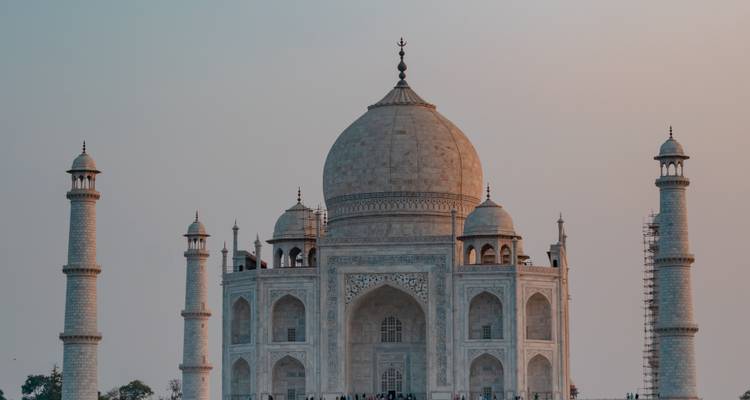 Die weiße Marmorkuppel und die Minarette des Taj Mahal leuchten sanft gegen einen Himmel in Pastellfarben bei Tagesanbruch.
