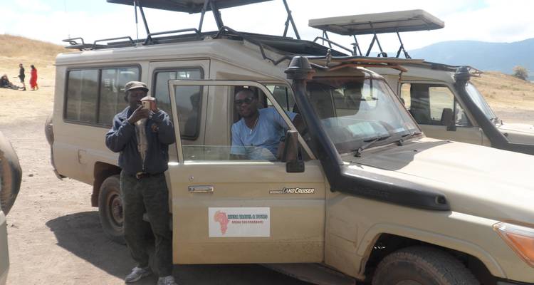 Safarifahrzeug mit Fahrer, der für ein Foto posiert.