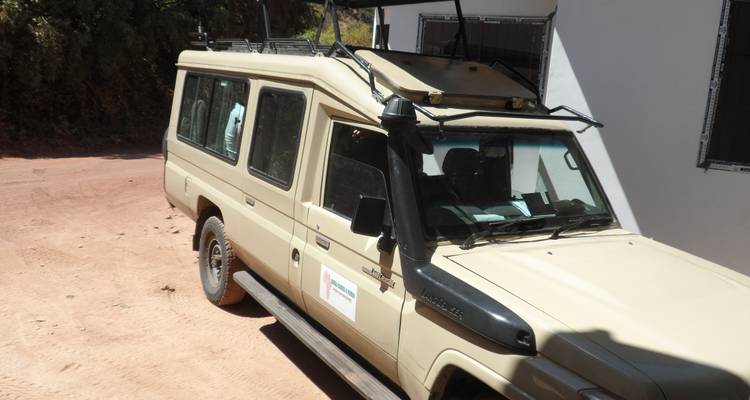 Safari-Fahrzeug in der Nähe eines Gebäudes geparkt.