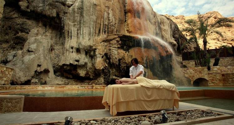 Une personne recevant un massage en plein air près d'une cascade dans un cadre serein.