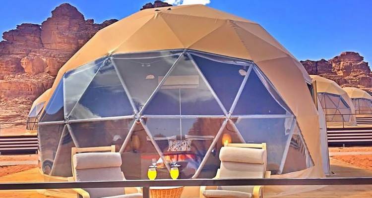 Vue rapprochée d'un dôme de glamping avec des chaises dans le désert.