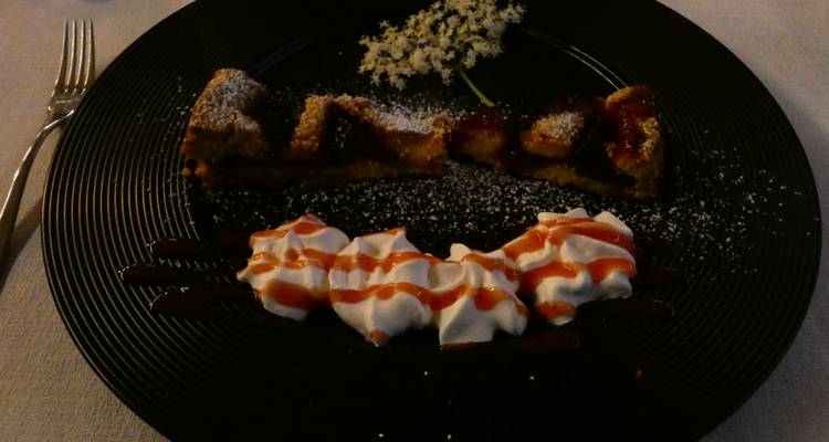 Zwak verlichte dessertschotel met slagroom en fruittoortjes op donker serviesgoed.